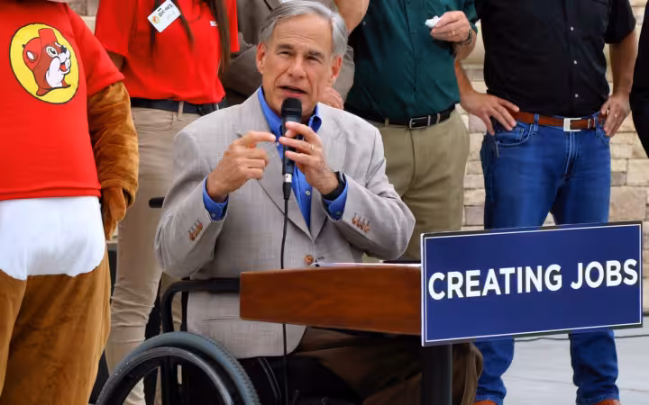 Texas Governor Greg Abbott speaking at a podium during Buc-ee's grand opening in Luling, Texas.
