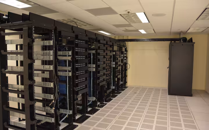 Rows of black server racks inside a data center room.