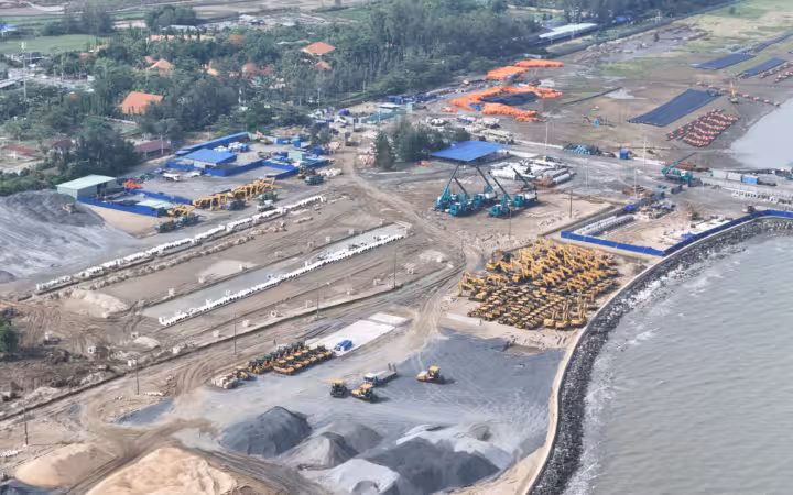 Aerial view of a construction site near water with machinery and buildings
