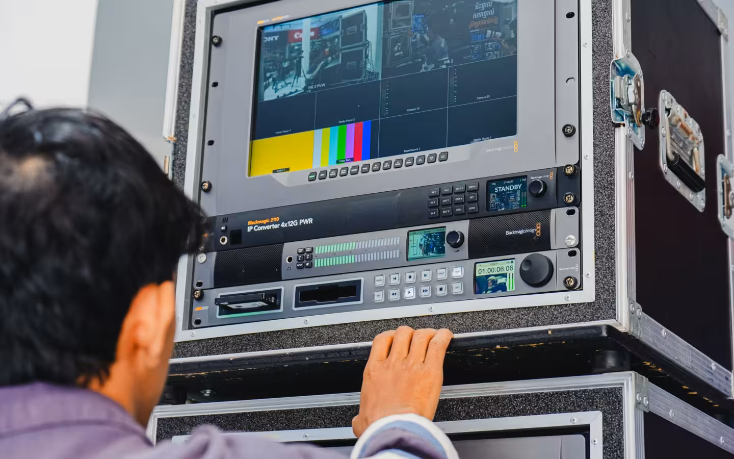 A technician manages professional broadcasting equipment in a control room setting.