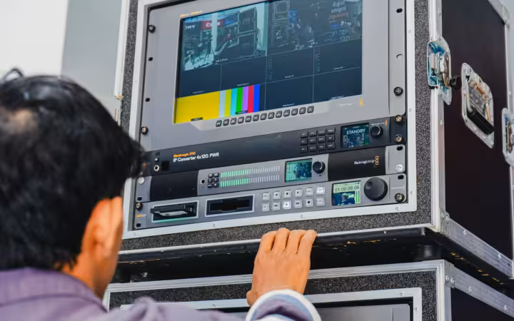 A technician manages professional broadcasting equipment in a control room setting.