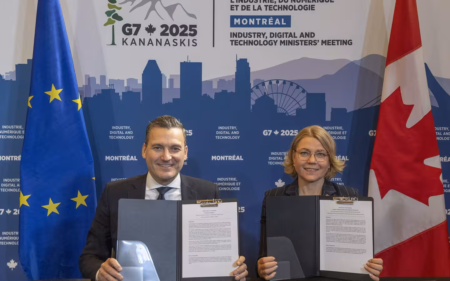 Evan Solomon and Henna Virkkunen holding folders in front of a G7 backdrop
