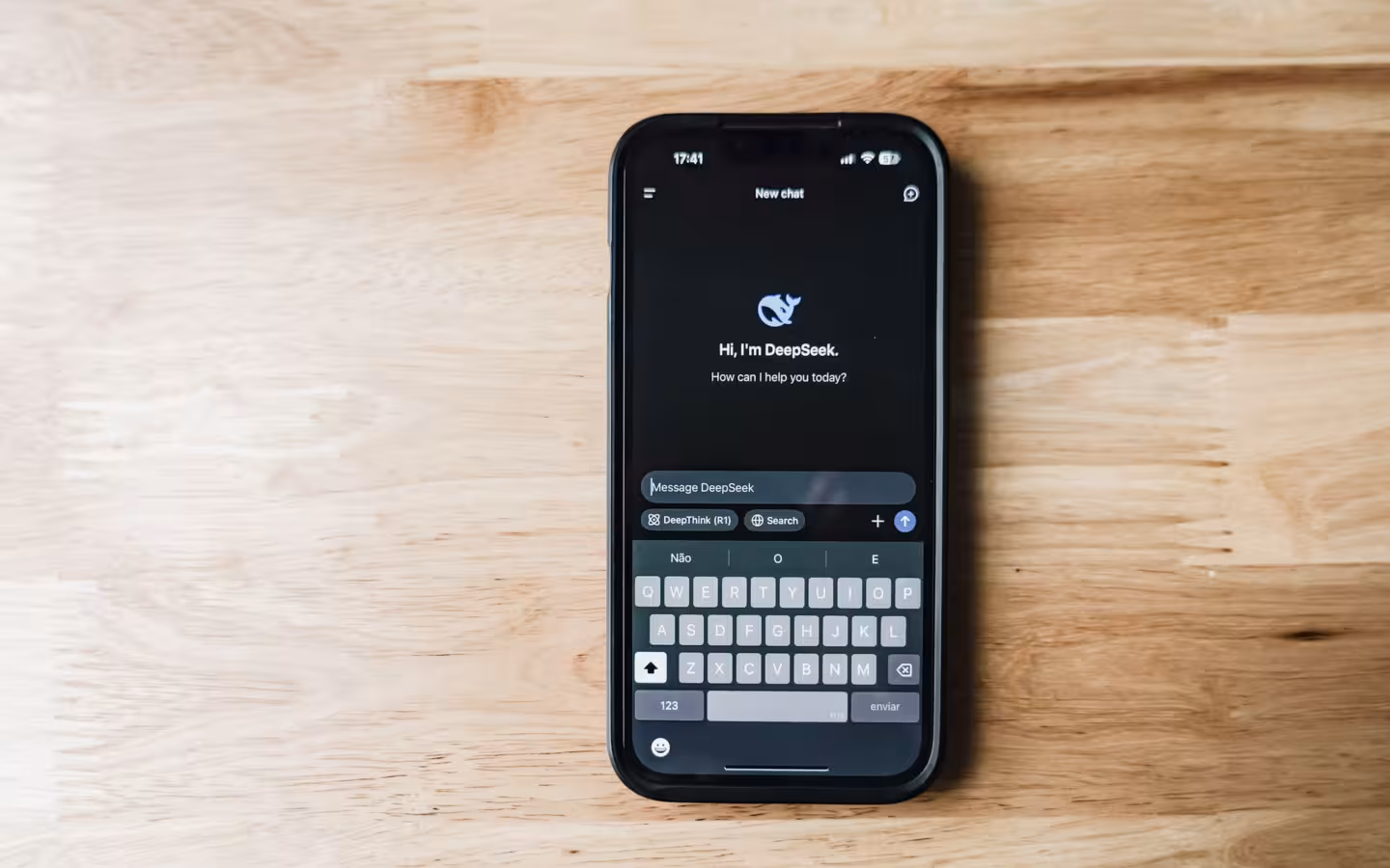 A smartphone on a wooden table showing an AI chatbot interface called DeepSeek
