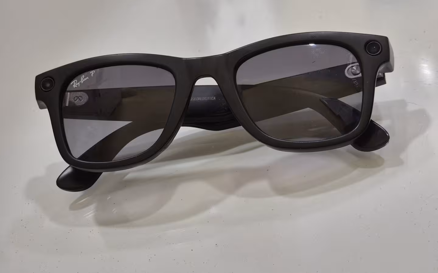 Black Ray-Ban Meta glasses with Polaroid lenses on white surface