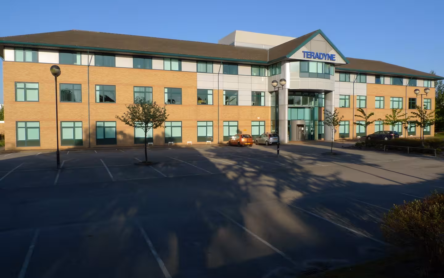 The Teradyne building, Birdhall Lane, a low brick office building with a large parking lot