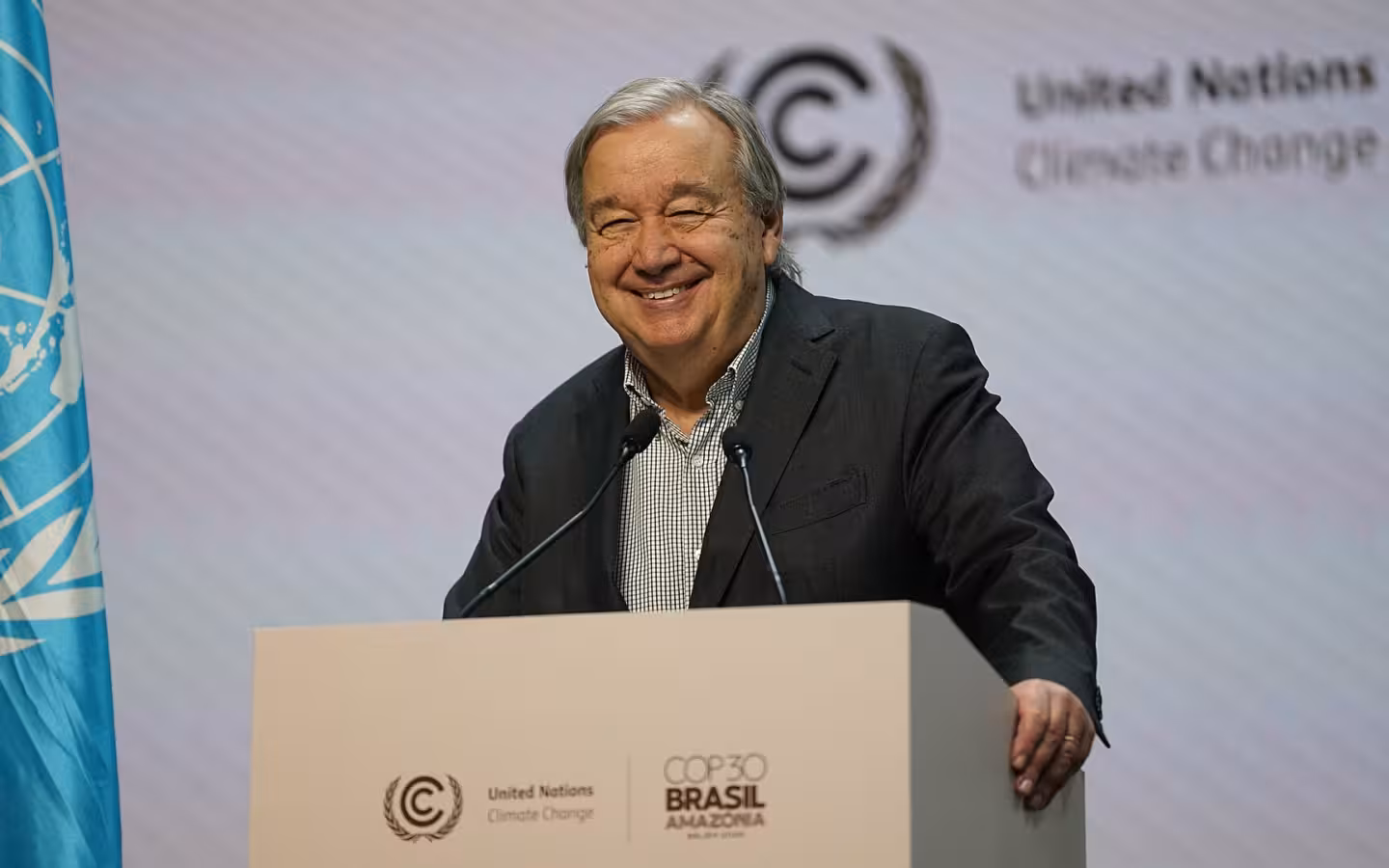 António Guterres smiling behind a podium at an event