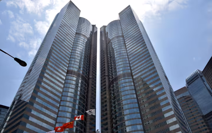 Two tall glass skyscrapers reaching up against a cloudy blue sky.