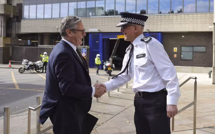 Keir Starmer shaking hands with a Metropolitan Police officer outside a police station