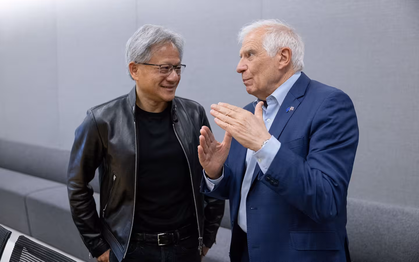 Two men talking indoors, one wearing a black leather jacket