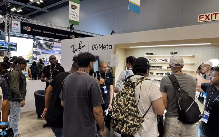 Attendees at a trade show booth displaying Ray Ban Meta smart glasses.