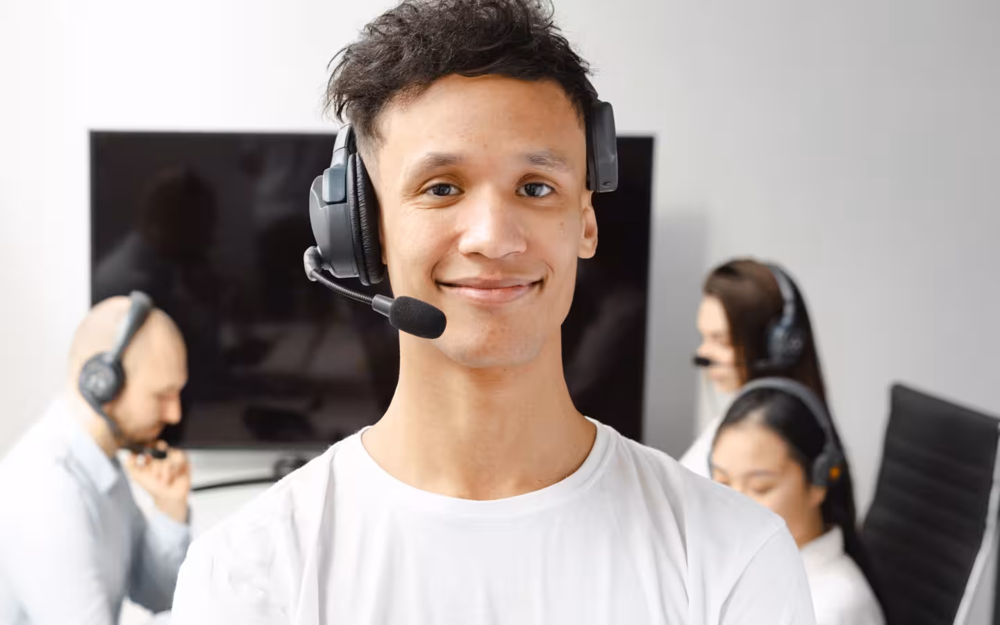 A smiling young call center agent wearing a headset in an office