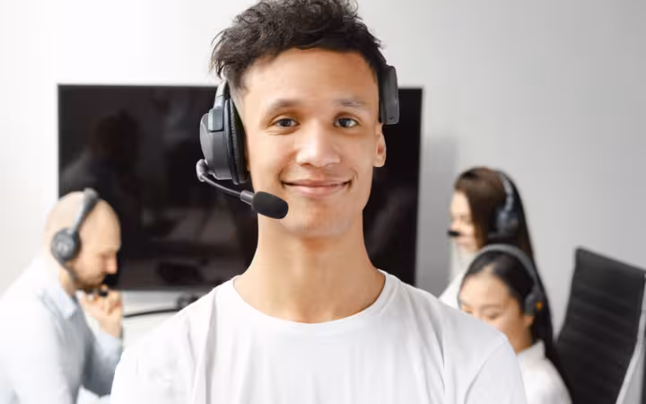 A smiling young call center agent wearing a headset in an office