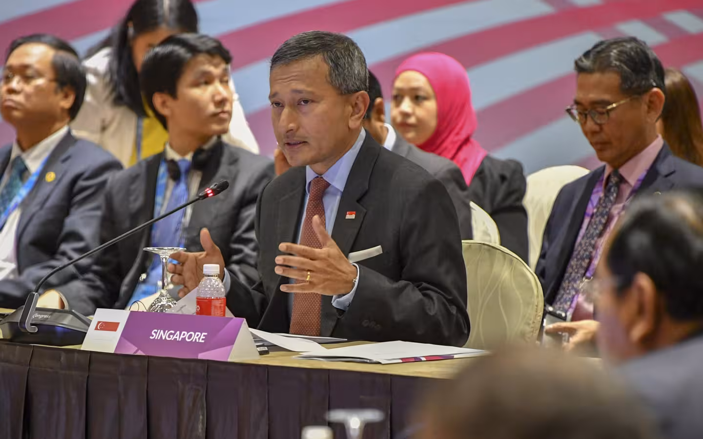 Vivian Balakrishnan speaking at a conference table with other delegates seated behind him