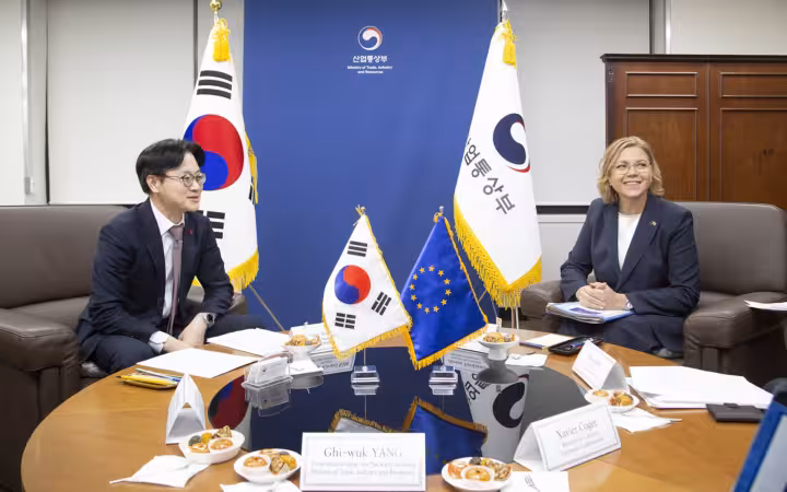 Kim Jung-kwan and Henna Virkkunen seated at a round table with flags