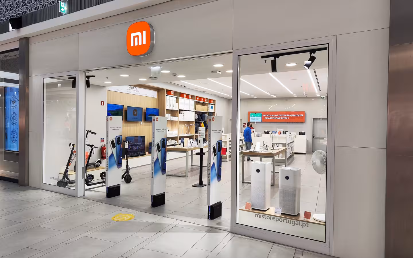 A brightly lit Xiaomi storefront in a shopping mall with products on display inside