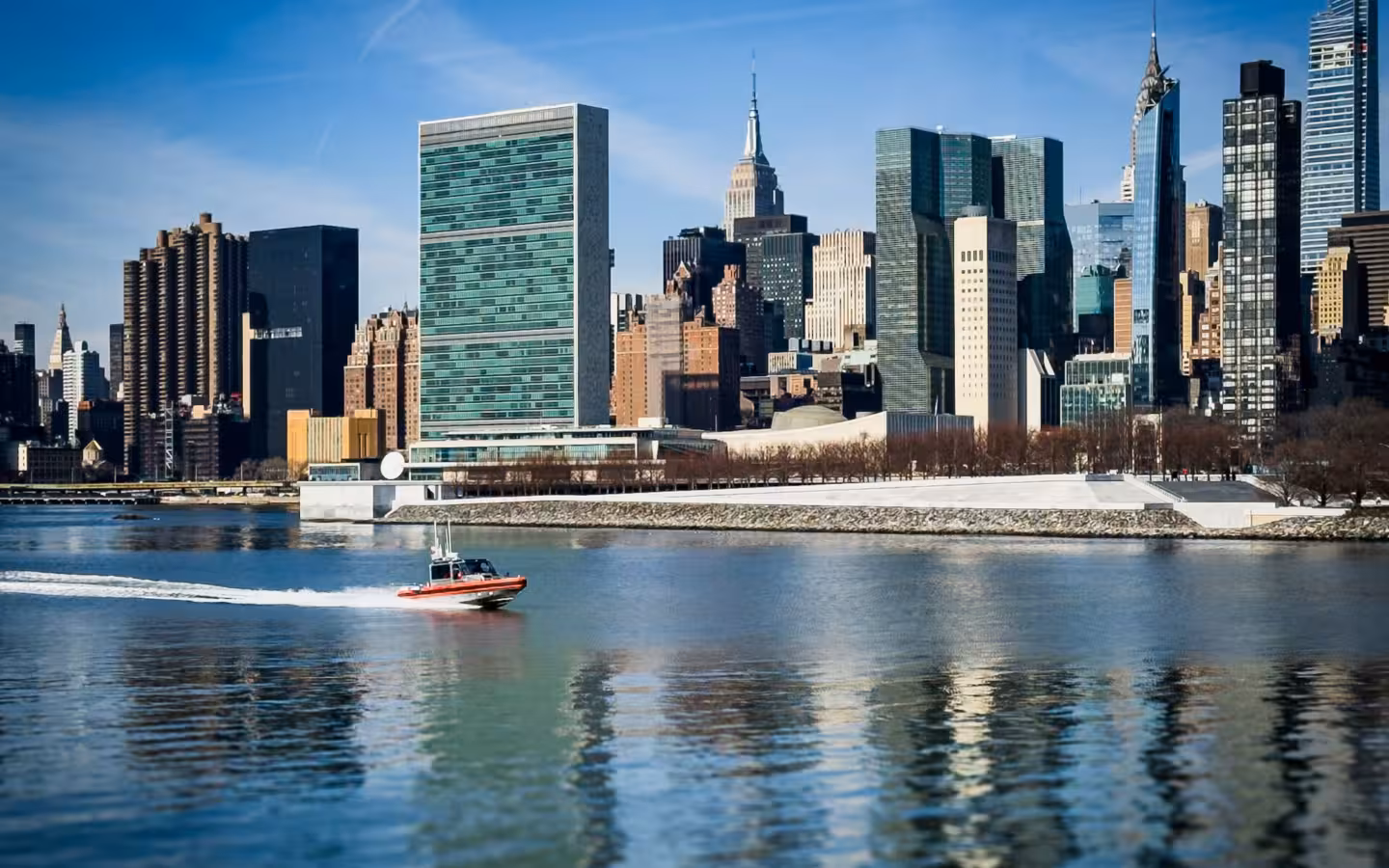 Boat passing United Nations Headquarters and surroundings on the East River