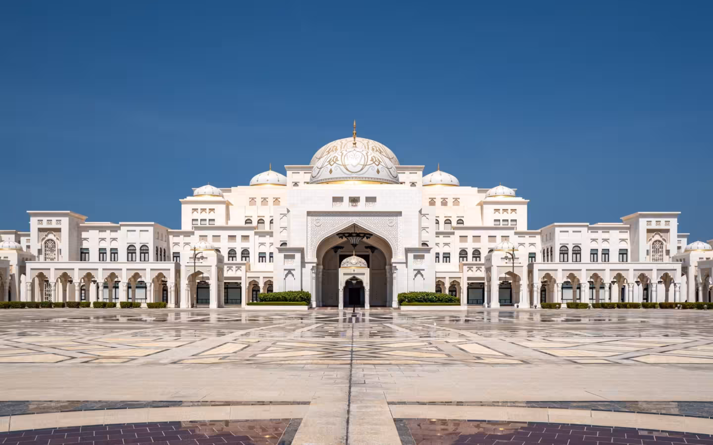 Qasr Al Watan Palace stands across a broad plaza beneath a clear sky.