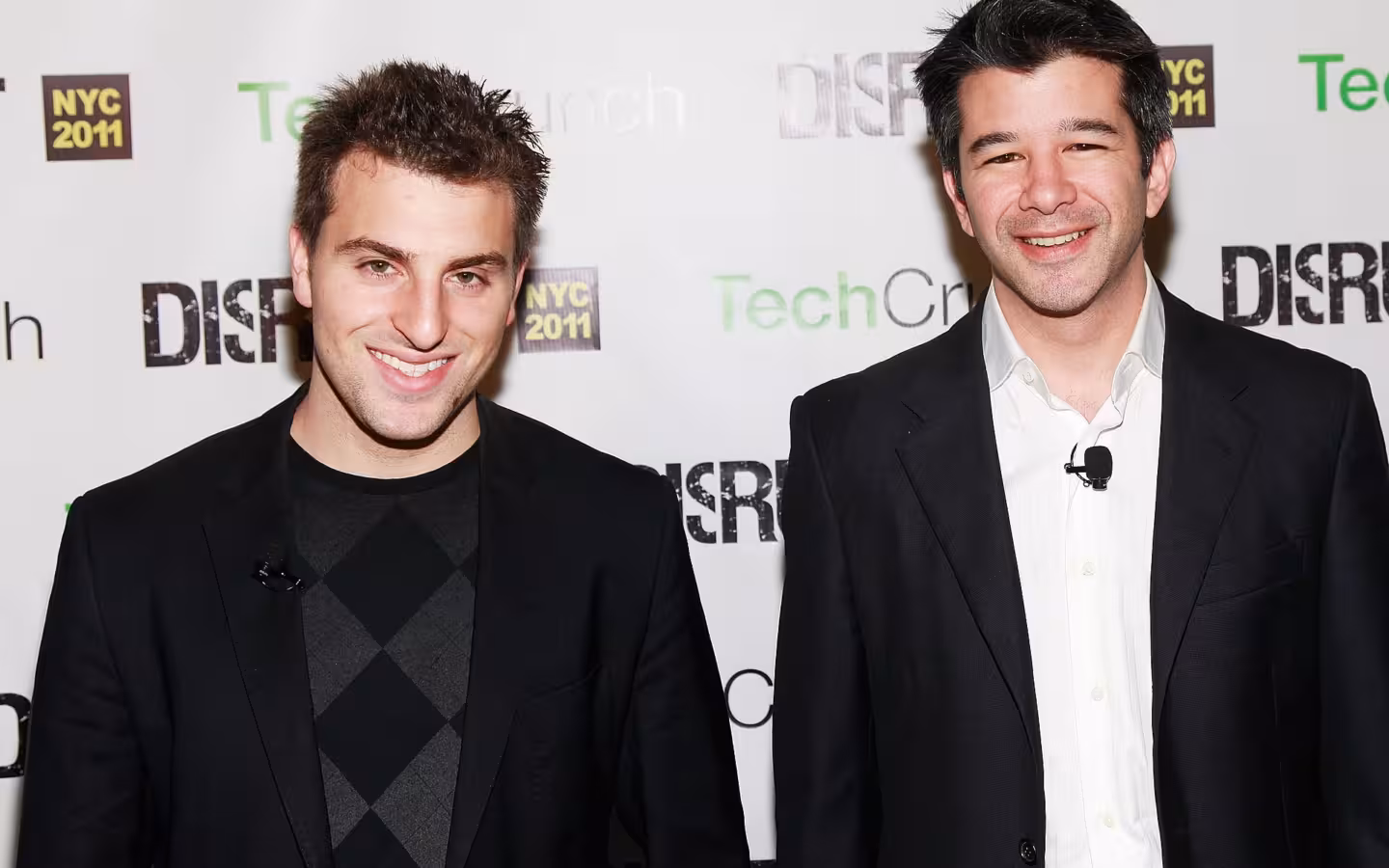 Brian Chesky and Travis Kalanick pose before a TechCrunch Disrupt backdrop.