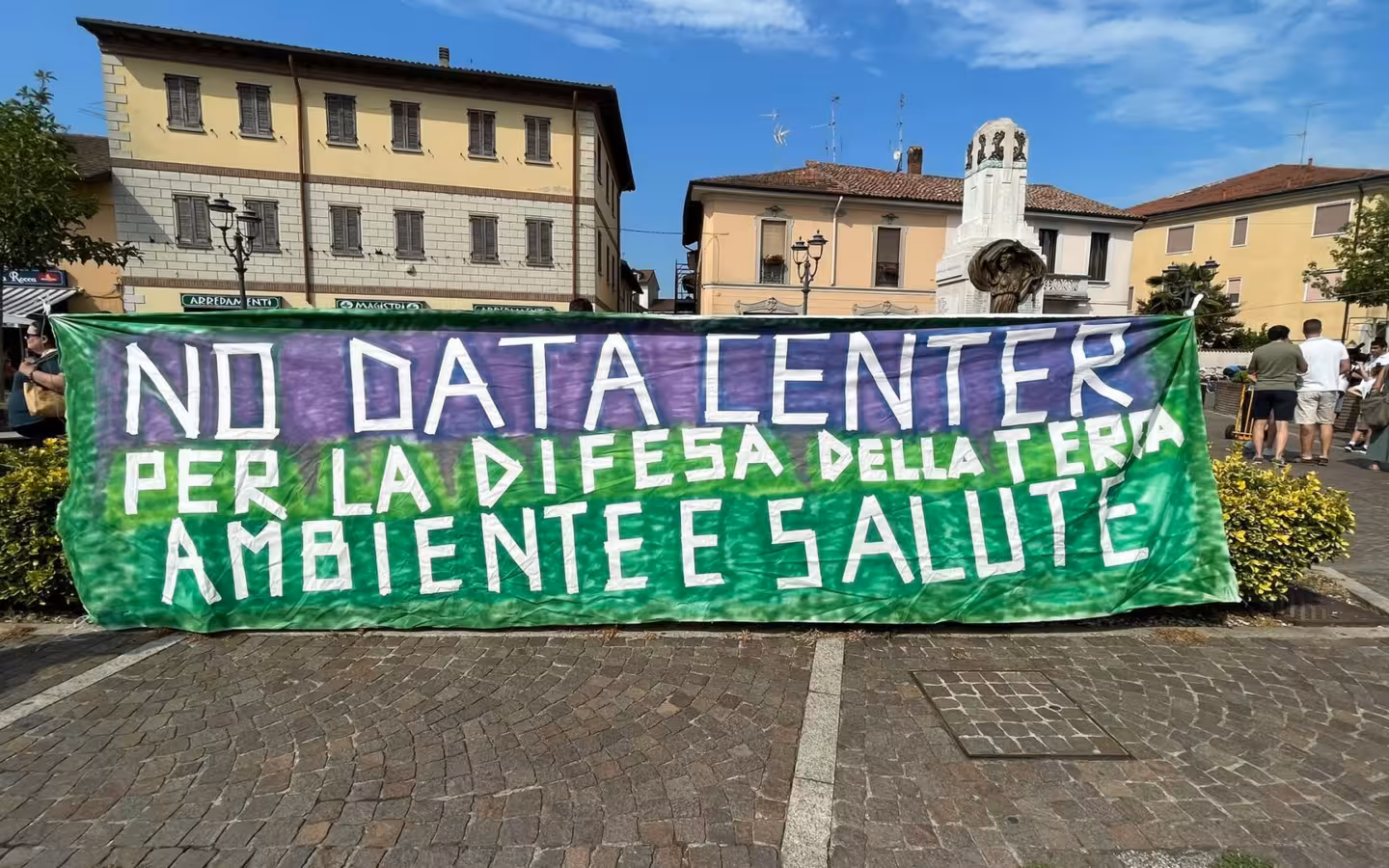 An anti-data-centre protest banner stretches across a town square.