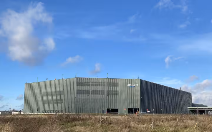 Amazon.com distribution center in Antwerp beneath a blue, cloud-filled sky