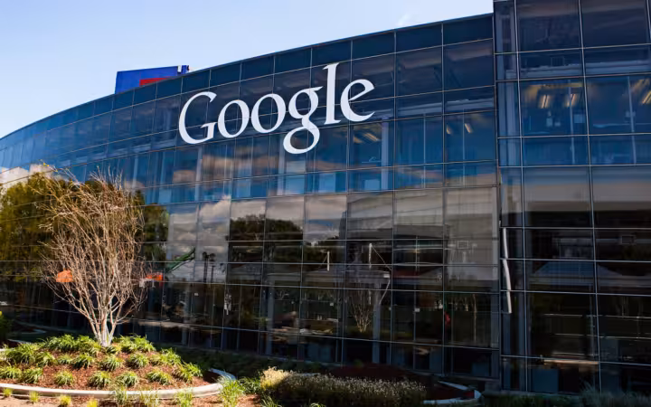 Google headquarters’ glass facade with a large logo and landscaped trees