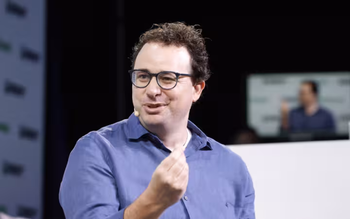 Anthropic CEO Dario Amodei speaks onstage wearing a headset microphone.