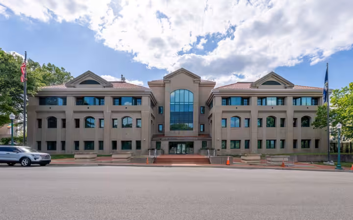 Office of Foreign Missions building across a road beneath partly cloudy skies