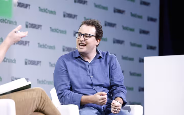 Dario Amodei speaking onstage at TechCrunch Disrupt 2023, beside an interviewer.