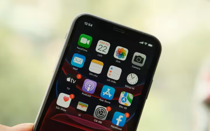 A tilted smartphone showing App Store and other apps against a blurred background