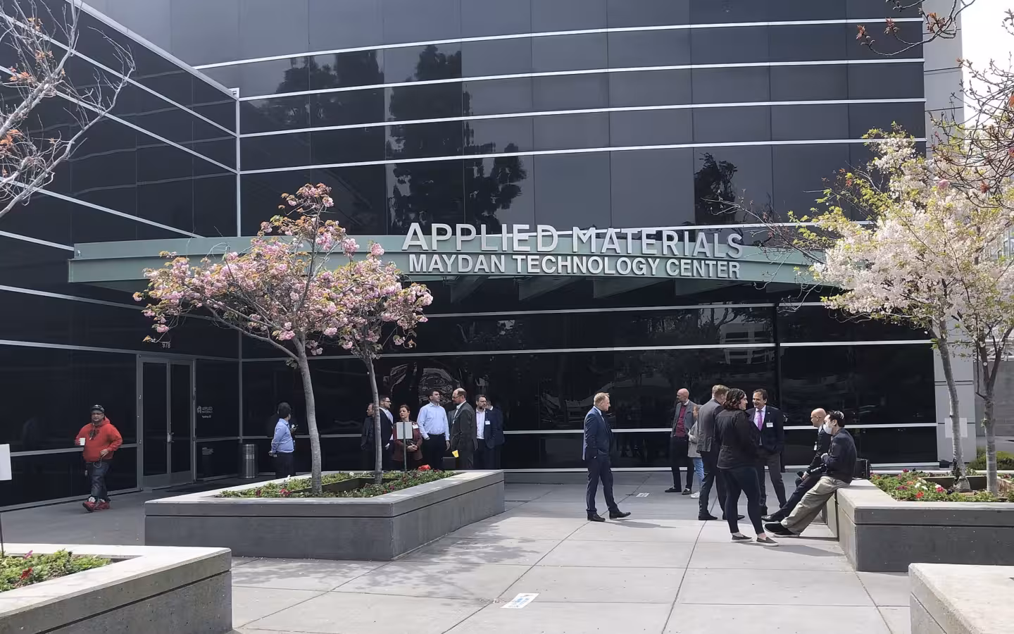 Applied Materials’ Maydan Technology Center entrance, with people and flowering trees outside