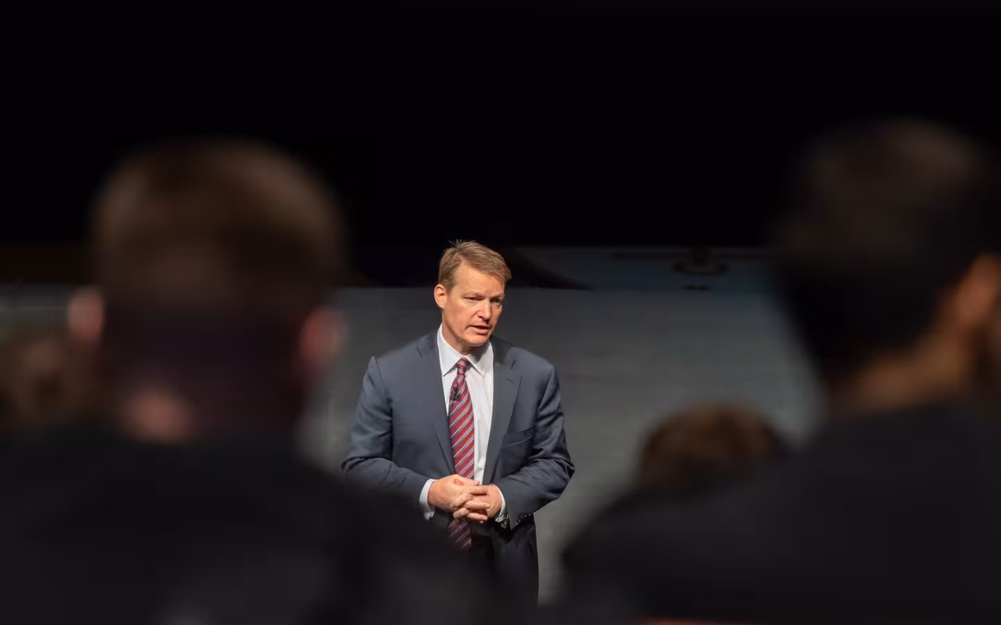 Kevin Mandia speaks at a cyber lecture behind blurred audience members.