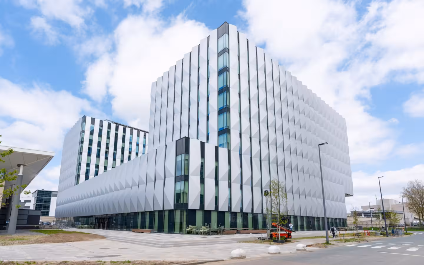 A modern ASML building with a white geometric facade beneath a blue sky