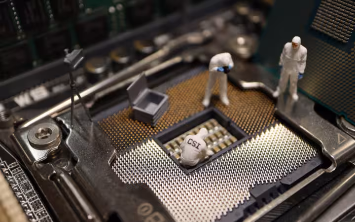 Miniature CSI figures in white suits investigate a computer processor socket.