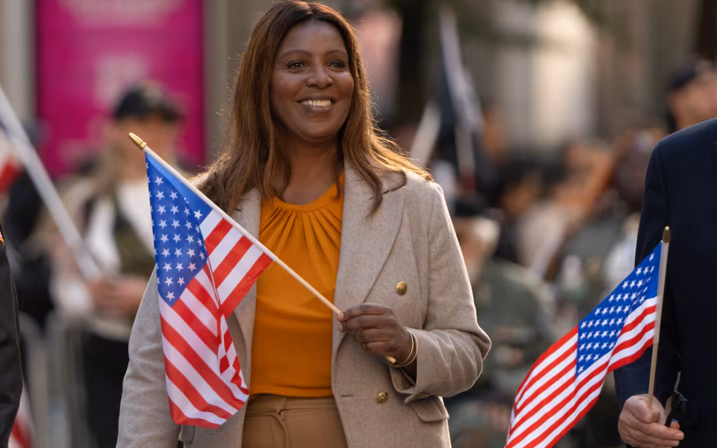 Letitia James smiles and carries an American flag at a parade.