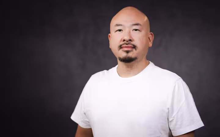 Jason Kwon poses in a white shirt against a dark backdrop.