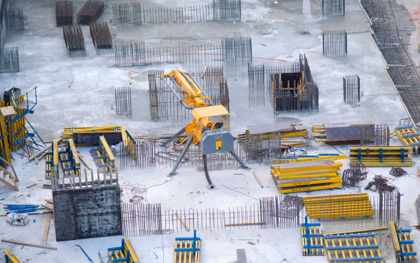 An aerial view of a construction site with machinery, rebar and materials