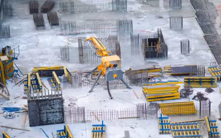 An aerial view of a construction site with machinery, rebar and materials