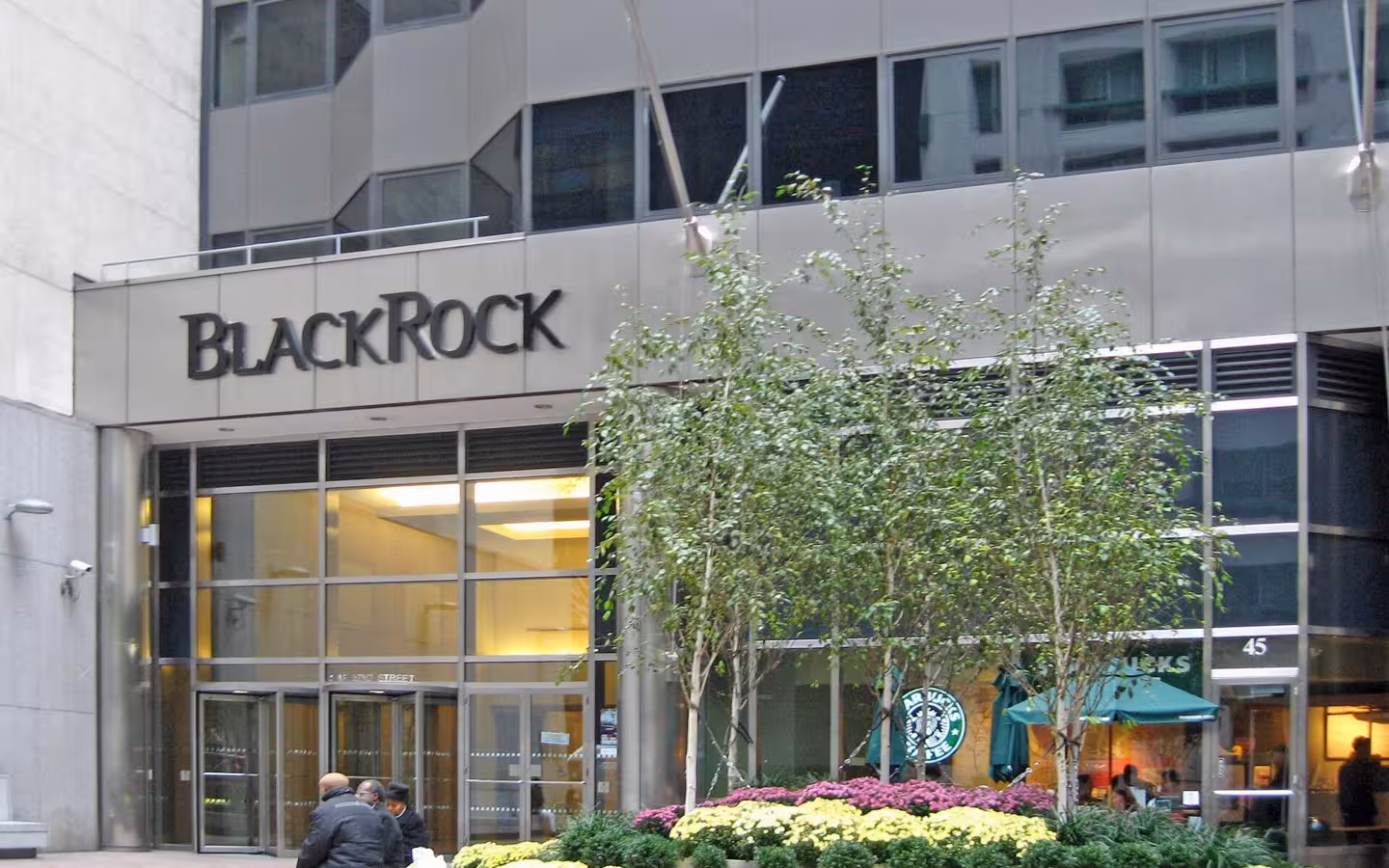 BlackRock headquarters entrance with its sign, trees and flower beds.