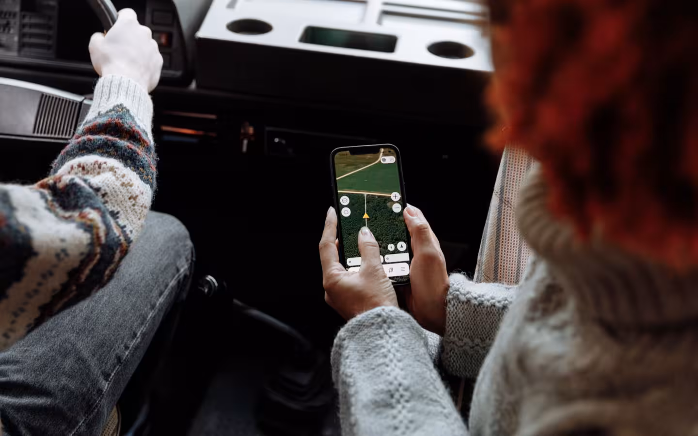 Two people in a car use a smartphone navigation app.