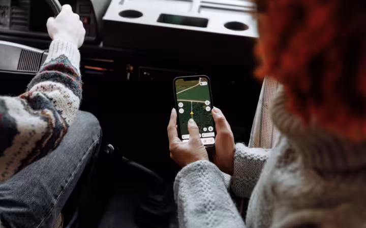 Two people in a car use a smartphone navigation app.