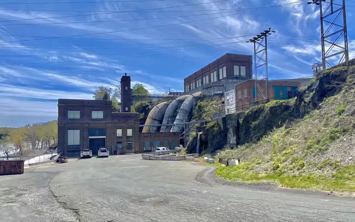 School Street Hydroelectric Station beside a broad paved lot and power lines.