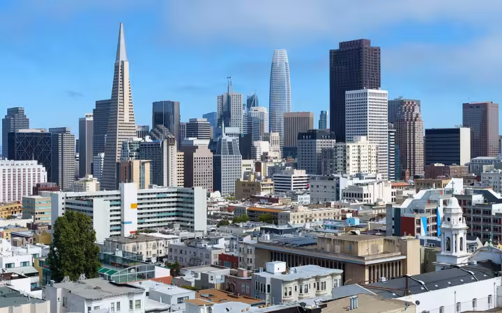 Wide-angle view of the San Francisco downtown skyline under a blue sky.