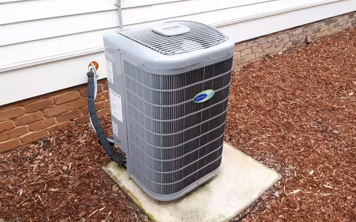 A Carrier heat pump unit beside a house, with its logo visible.