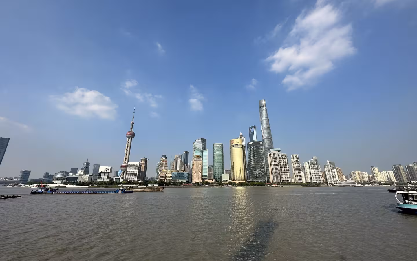 A clear, well-framed daytime view of the Shanghai skyline across a wide river.