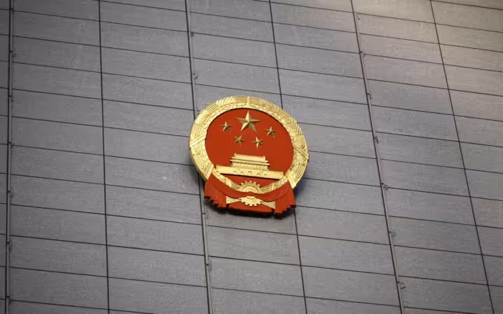 China’s national emblem mounted on a broad gray building facade
