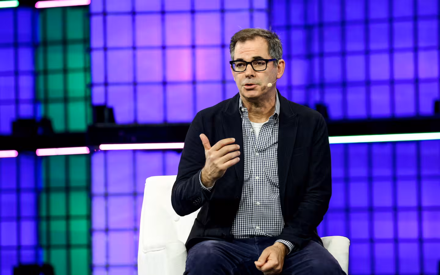 Michael Intrator speaking onstage at Web Summit 2024 against purple lighting