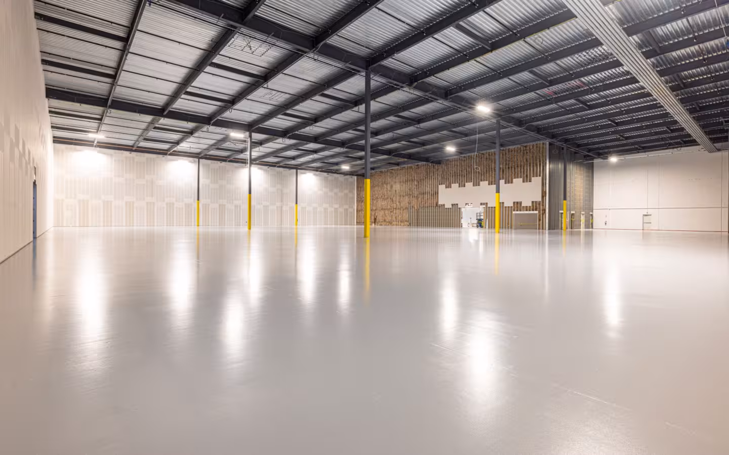 An empty modern warehouse interior with a polished floor and high ceiling