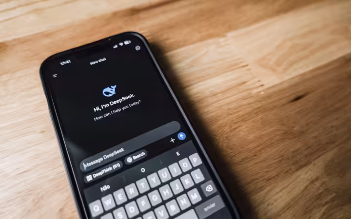 A smartphone displaying DeepSeek's chat interface lies on a wooden table.