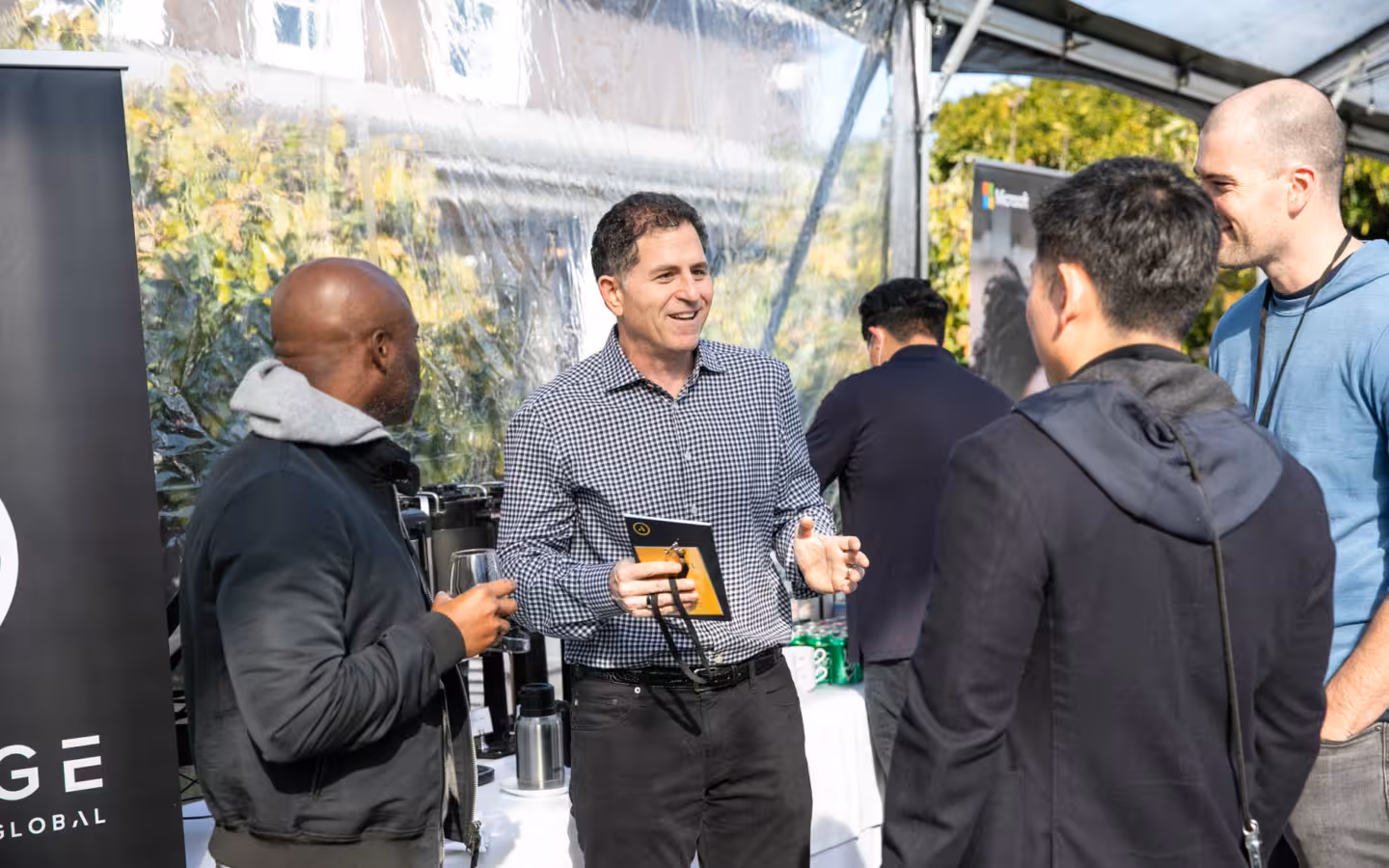 Michael Dell speaks with several people beneath a canopy at The Grove.
