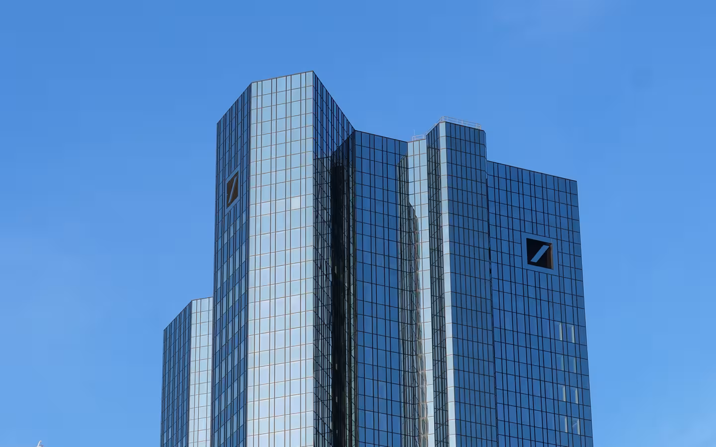 Deutsche Bank headquarters in Frankfurt, glass towers against a clear blue sky